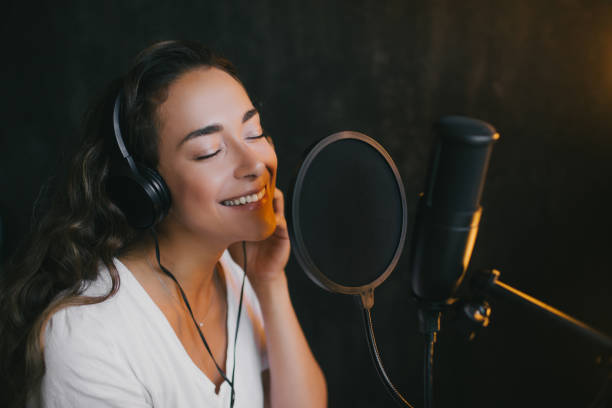 istock Young beautiful woman singing in microphone, recording voice in a studio. 1285979590