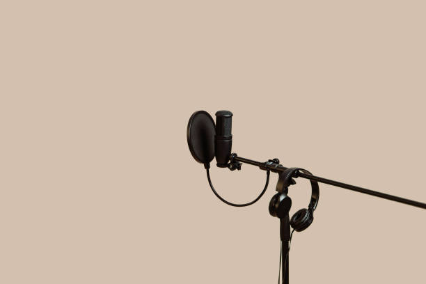 Items for podcasting: professional microphone and earphones isolated on beige  background. Place for text.