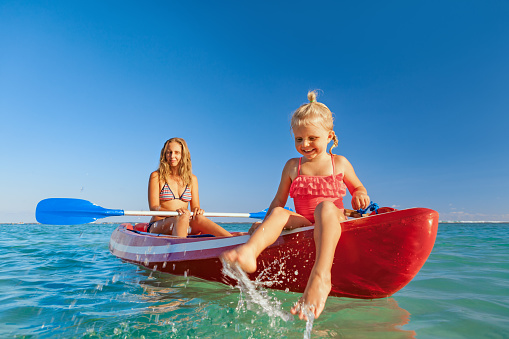 Happy family - young mother, children have fun on boat walk. Woman and child paddling on kayak. Travel lifestyle, parents with kids recreational activity, watersports on summer sea beach vacation.