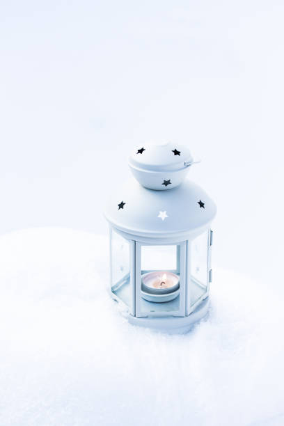 istock White Christmas lantern in snow, with yellow candle light, on white snow background 1285983897