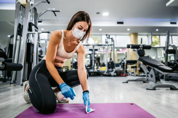 istock Fit woman cleaning exercise mat with disinfectant spray 1285988582