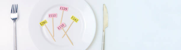 istock Harmful food additives. Knives, fork, plate. On the plate there are several tables with the E-supplement code. Copy space 1285989545
