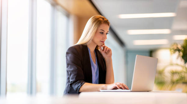 istock Young businesswoman using laptop in a modern office 1285990445