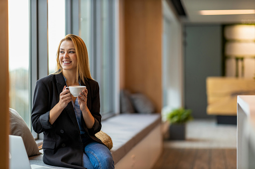 Smiling businesswoman with cup of coffee looking out of window