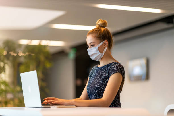 istock Businesswoman wearing protective face mask working in a modern office 1285992049