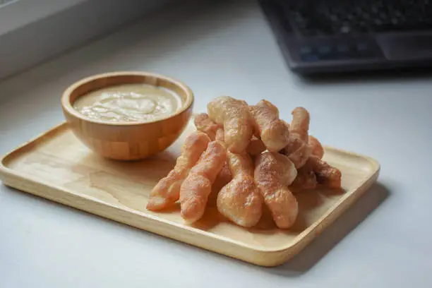 Photo of Soft focus of Youtiao or Cakwe with milktea custard on brown wooden background. Thailand street food  is call 