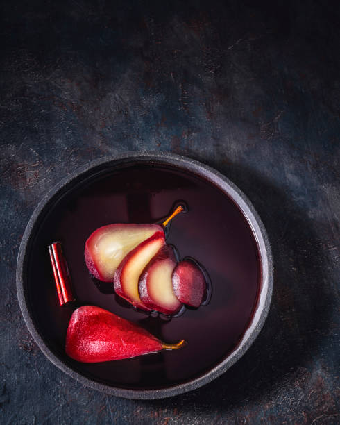 Poached pears in red wine recipe sliced served on dark plate minimalistic