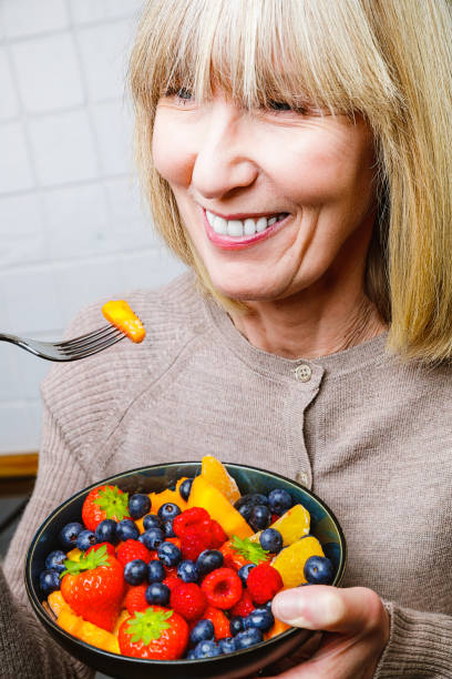 istock Attractive senior woman with fruit bowl 1285996989