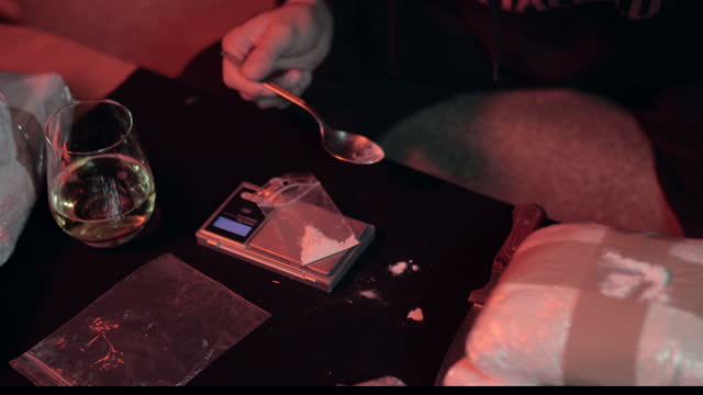 Drug Dealer preparing doses in dark room, drug trafficking.