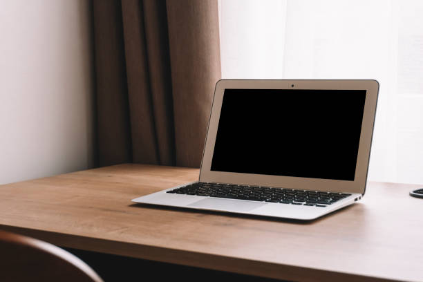 istock Laptop on work table in empty room or office. Off laptop with blank screen in the interior of the room. 1286002438