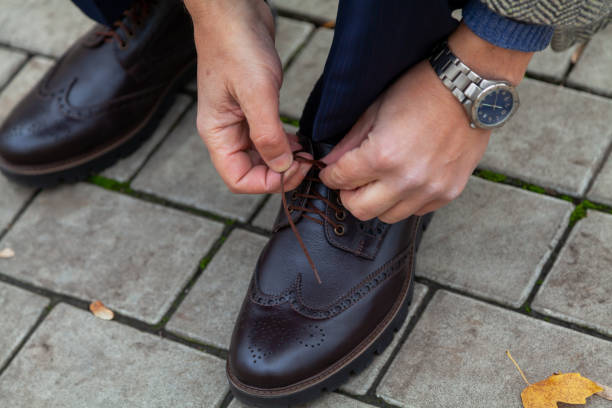 istock Man ties lace on brown shoe 1286002524