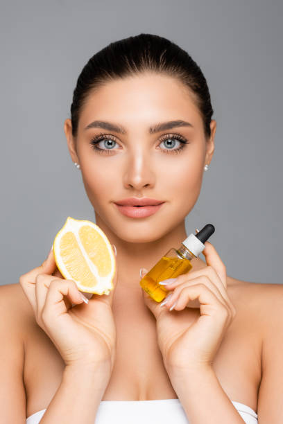 istock woman with serum and lemon half isolated on grey 1286003233