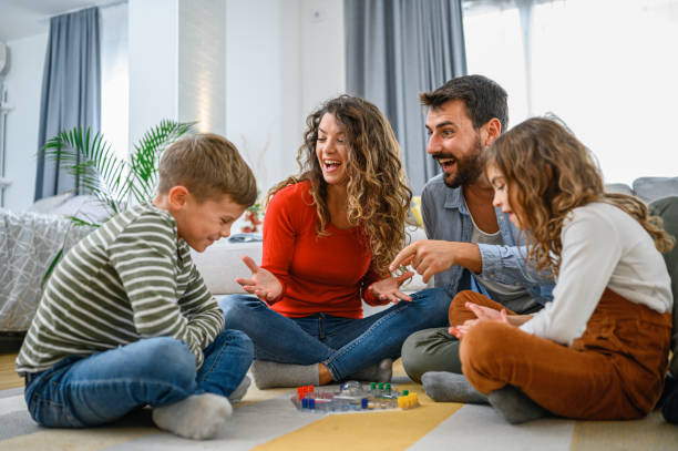 genitori allegri che giocano a giochi da tavolo con i loro figli. - sedere per terra foto e immagini stock