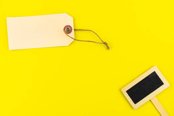 istock One blank brown gift tags with a string and a wooden tag on the right lying on a yellow background made of sponge. 1286003756