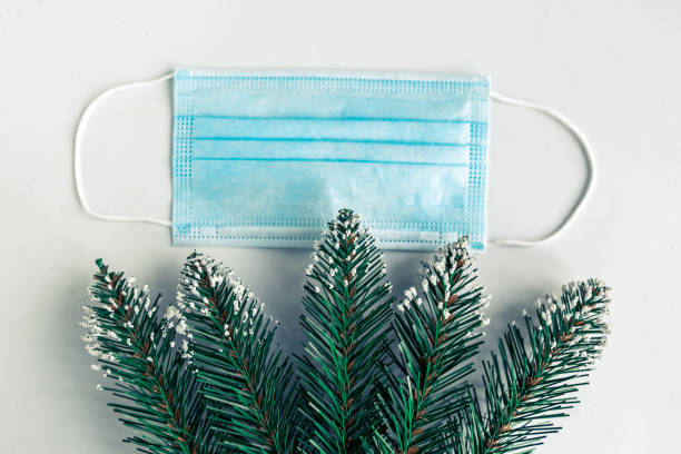 istock christmas tree branches and face mask on white background, coronavirus Christmas concept 1286006215