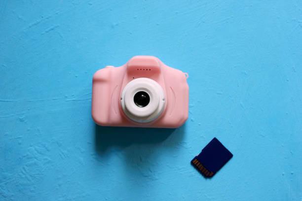 istock Children's camera on a blue background. A pink camera, a memory card. The camera is located in the middle. View from above. Hobby. Flatlay. Copy spase. 1286006775