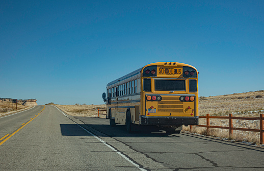 School bus on Utah desert road on blue sky background.