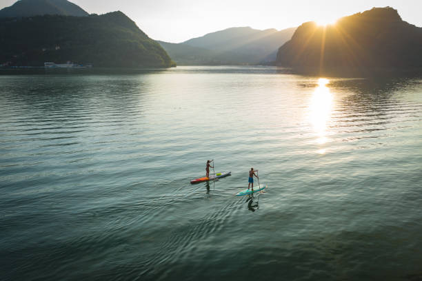 日没時の湖の上の2人のパドルボーダーの空中視点 - paddleboard oar women lake ストックフォトと画像