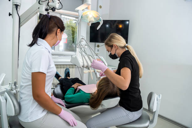Female dentist and young assistant doing repairing patient tooth in dental ambulant Female dentist and young assistant doing repairing patient tooth in dental ambulant. Doctor practice ambulant patient stock pictures, royalty-free photos & images