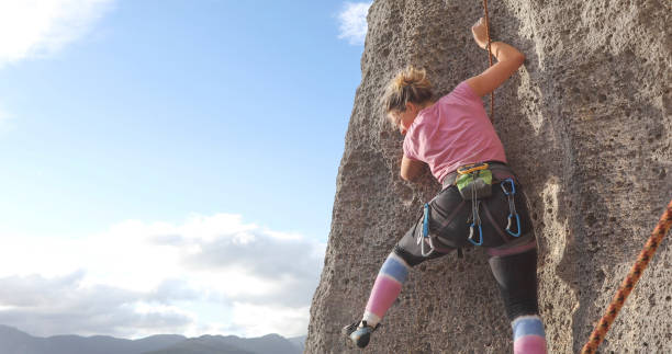 istock Young woman climbs steep rock face 1286012202