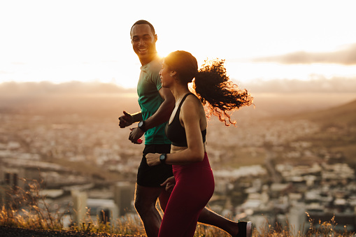 Fitness couple going for sunrise running. Fitness man and woman running on road.