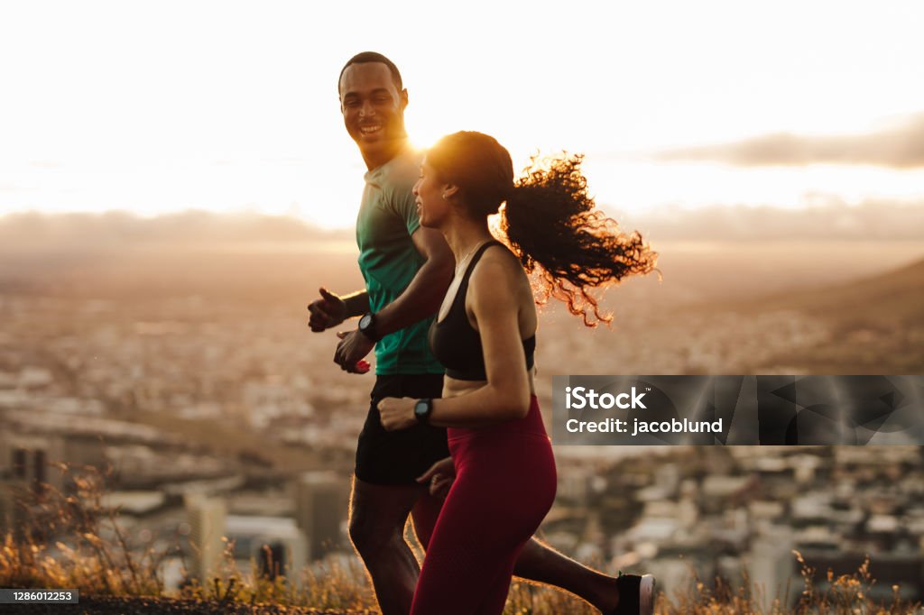 Couple running at sunrise Fitness couple going for sunrise running. Fitness man and woman running on road. Exercising Stock Photo