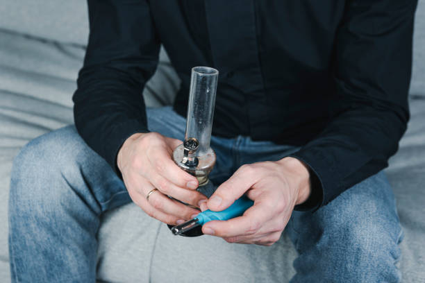 The young person smoking medical marijuana with bong, indoors. The young person smoking medical marijuana with bong, indoors. Cannabis is a concepts of alternative medicine and herbs bong photos stock pictures, royalty-free photos & images