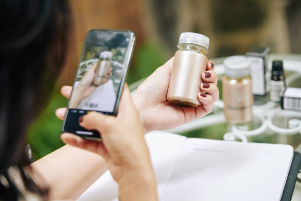 Woman photographing moisturising ampoule Close-up image of businesswoman taking photo of moisturising ampoule jar on smartphone for her online shop selling photos stock pictures, royalty-free photos & images