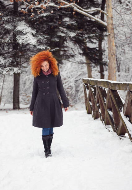 Young beautiful woman in warm clothing enjoying outdoors while walking in the winter forest