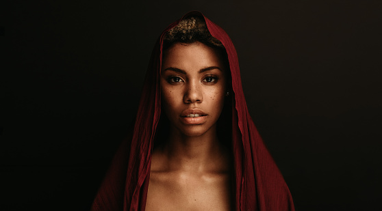 Portrait of african american woman on black background. Woman wearing maroon fabric on head isolated on black background.