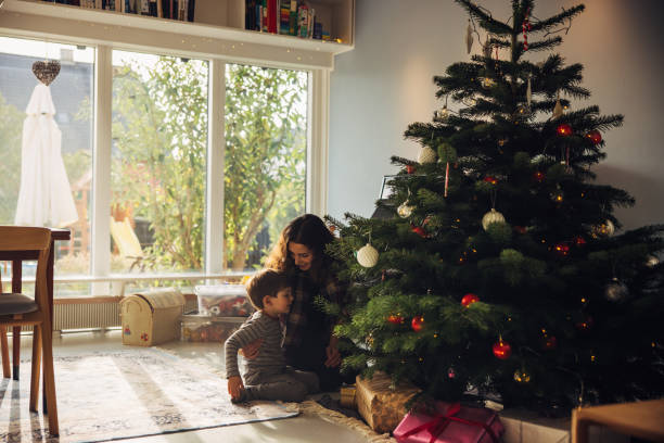 istock Mother and son sitting by Christmas tree 1286015700
