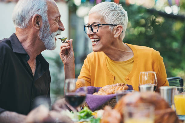 mulher idosa brincalhão alimentando o marido em uma festa no jardim - healthy feeding - fotografias e filmes do acervo