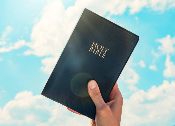 istock man hand Holy Bible sky background 1286015911