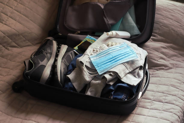 istock Open suitcase with clothes pills with anti-virus protactive masks 1286022164