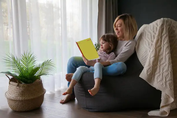 Photo of Mother reading book to her little daughter