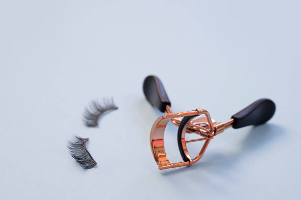 istock Curler and false eyelashes on blue background, close up 1286022551
