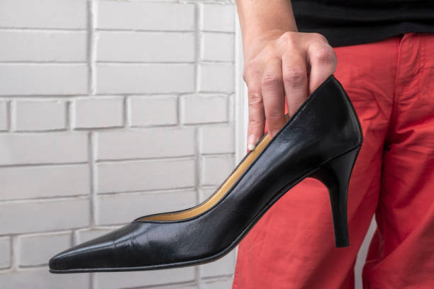 istock Woman hand holds black high heel shoe. 1286022573