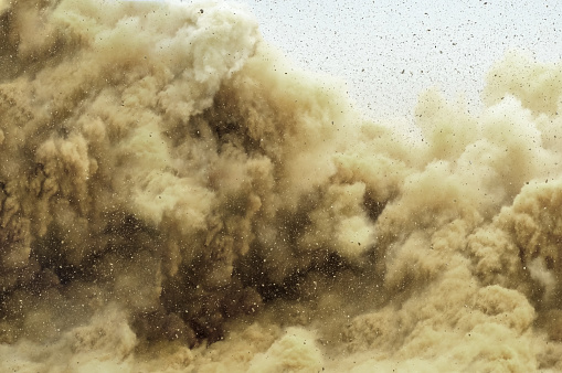 Rock particles and dust storm after detonator blast on the construction site in the middle east