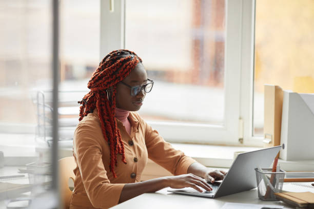 istock Young African-American Woman using Laptop at Desk 1286023656