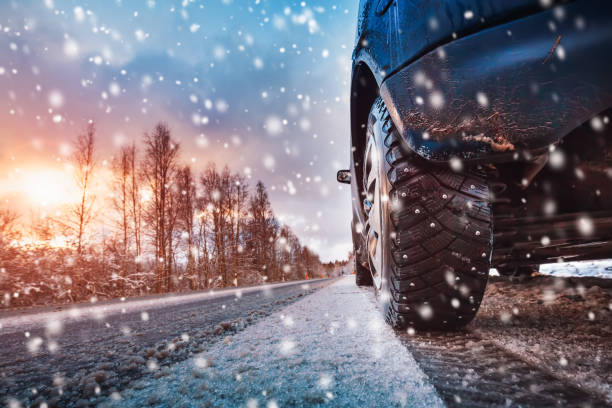 pneus de voiture sur la route d’hiver couverte de neige - winter driving photos et images de collection