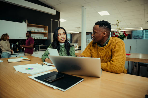 istock Young entrepreneurs discussing work while researching on laptop and digital tablet sitting in office 1286025287