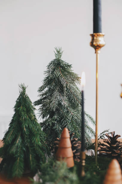 istock Christmas trees, candles and pine cones on rustic table. Festive modern zero waste decor 1286026550