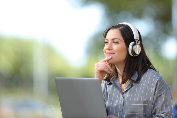 istock Woman with laptop and headphones thinks looking at side 1286027345