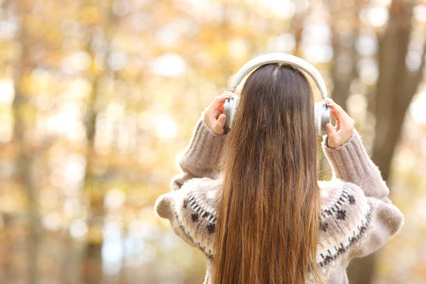 vista trasera de la mujer poniendo auriculares en otoño - mountain stream fotografías e imágenes de stock