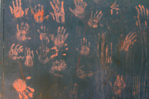 Hand prints stamped on a wall with dirt on a sunny day
