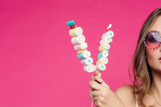 istock Seductive girl in pink sunglasses posing with marshmallow candy. 1286029416
