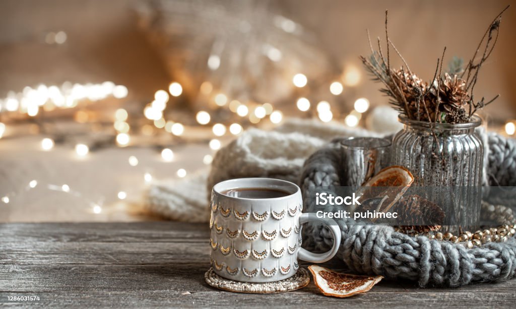Cozy composition with a Christmas cup on a blurred background with lights. Winter composition with a beautiful cup of hot drink on a blurred background with bokeh. Christmas Stock Photo