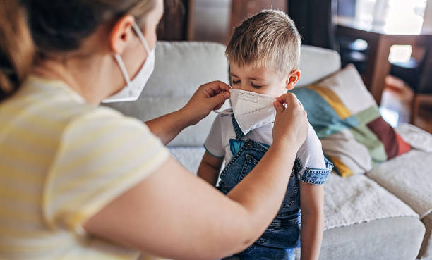 istock Pregnant mother putting protective face mask on her son 1286032594