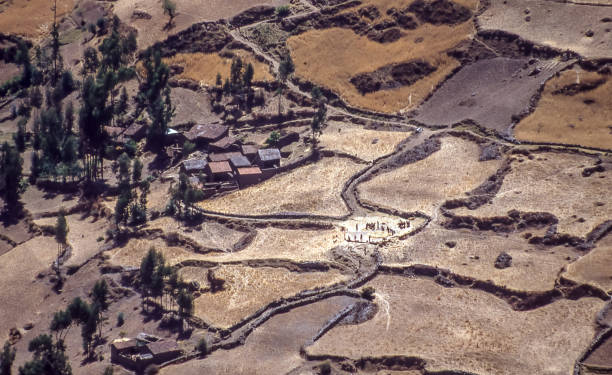 Terraced fields on the Andean highlands, Peru. Aerial view of terraced fields near an Andean village with farmers threshing corn on a farmyard. huari stock pictures, royalty-free photos & images
