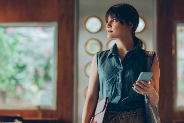 istock Telecommuting: Beautiful Young Freelancer Holding Entering a Cafe with her Work Essentials in her Hands 1286034589